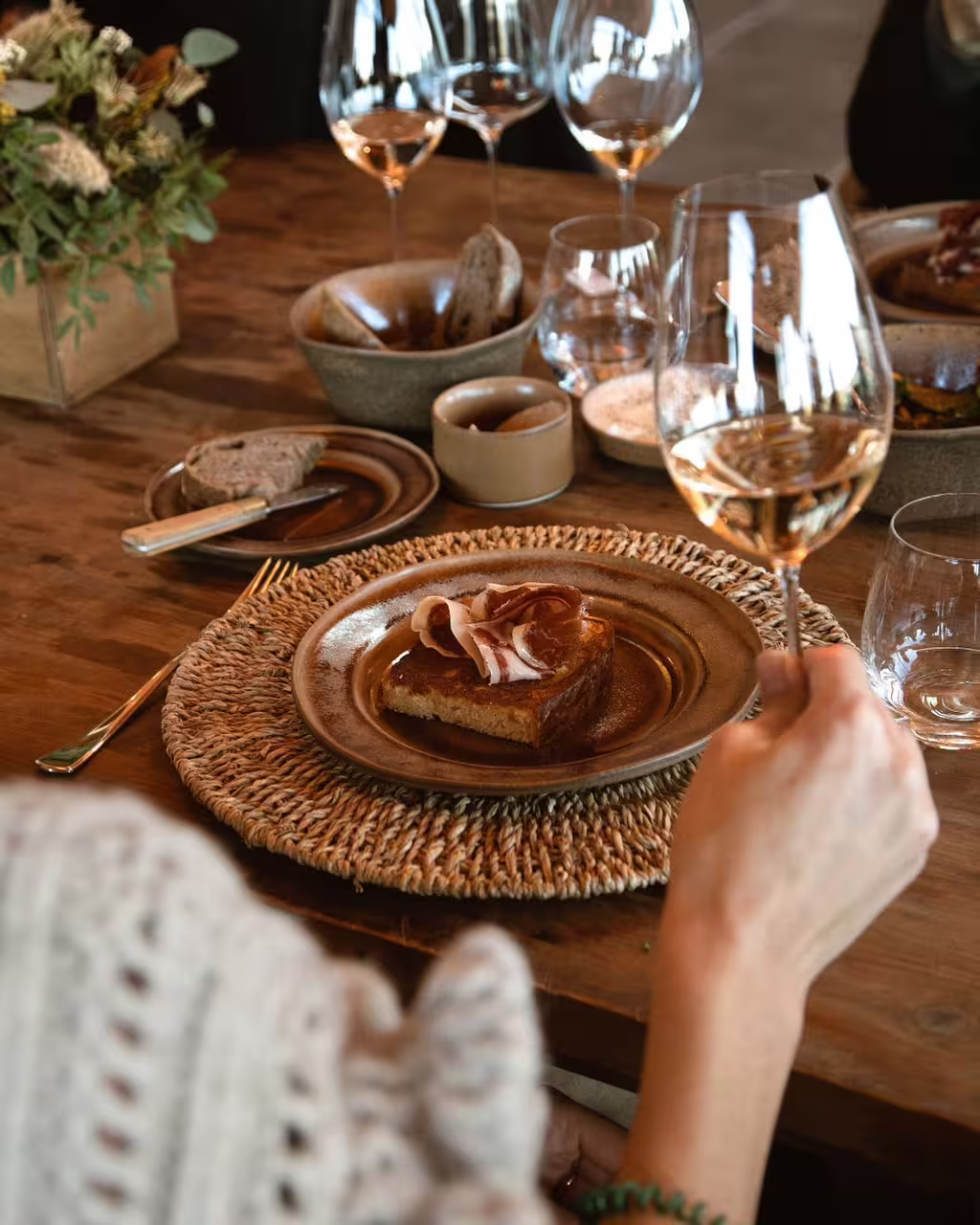 Elegant wine tasting experience with three glasses of wine paired with gourmet appetizers on a rustic wooden table setting.