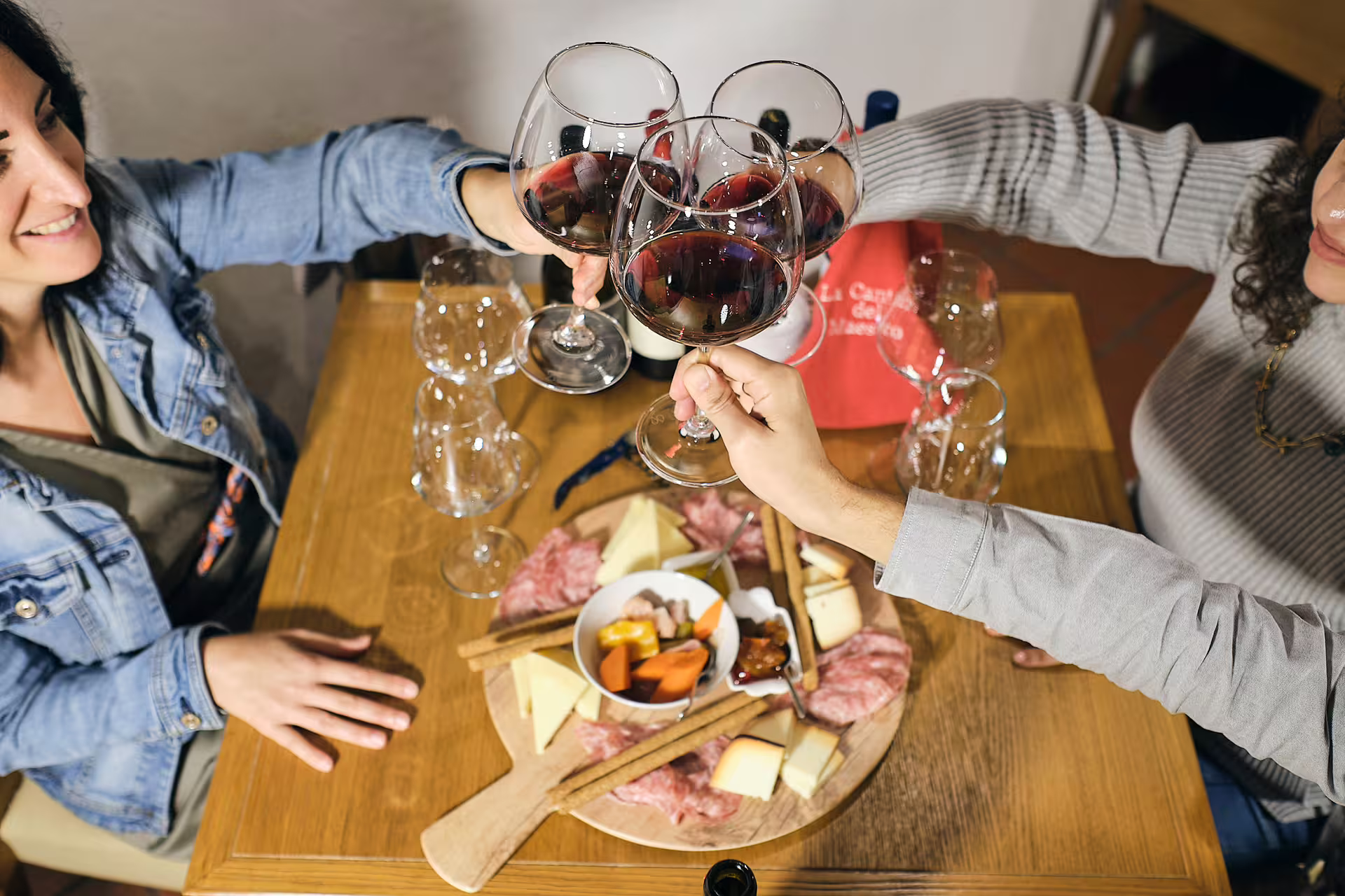 Friends clinking red wine glasses with local cheese and salumi on a Verona wine tasting near Juliet’s House
