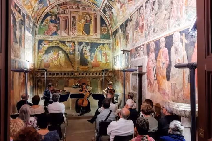 Guests enjoy a classical music performance in a fresco-adorned chapel, part of the Wine Tour South of Rome experience.