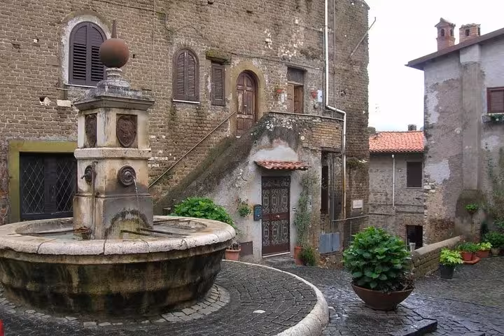 Charming old stone courtyard with a rustic fountain in a quaint village south of Rome on a wine tour.