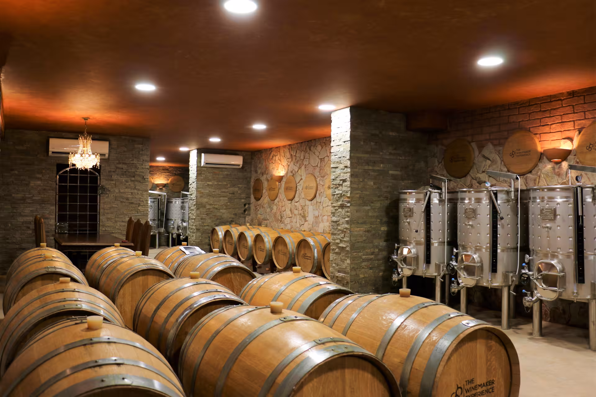 Rustic winery cellar with oak aging barrels and stainless steel tanks on a guided free-flow wine tasting tour