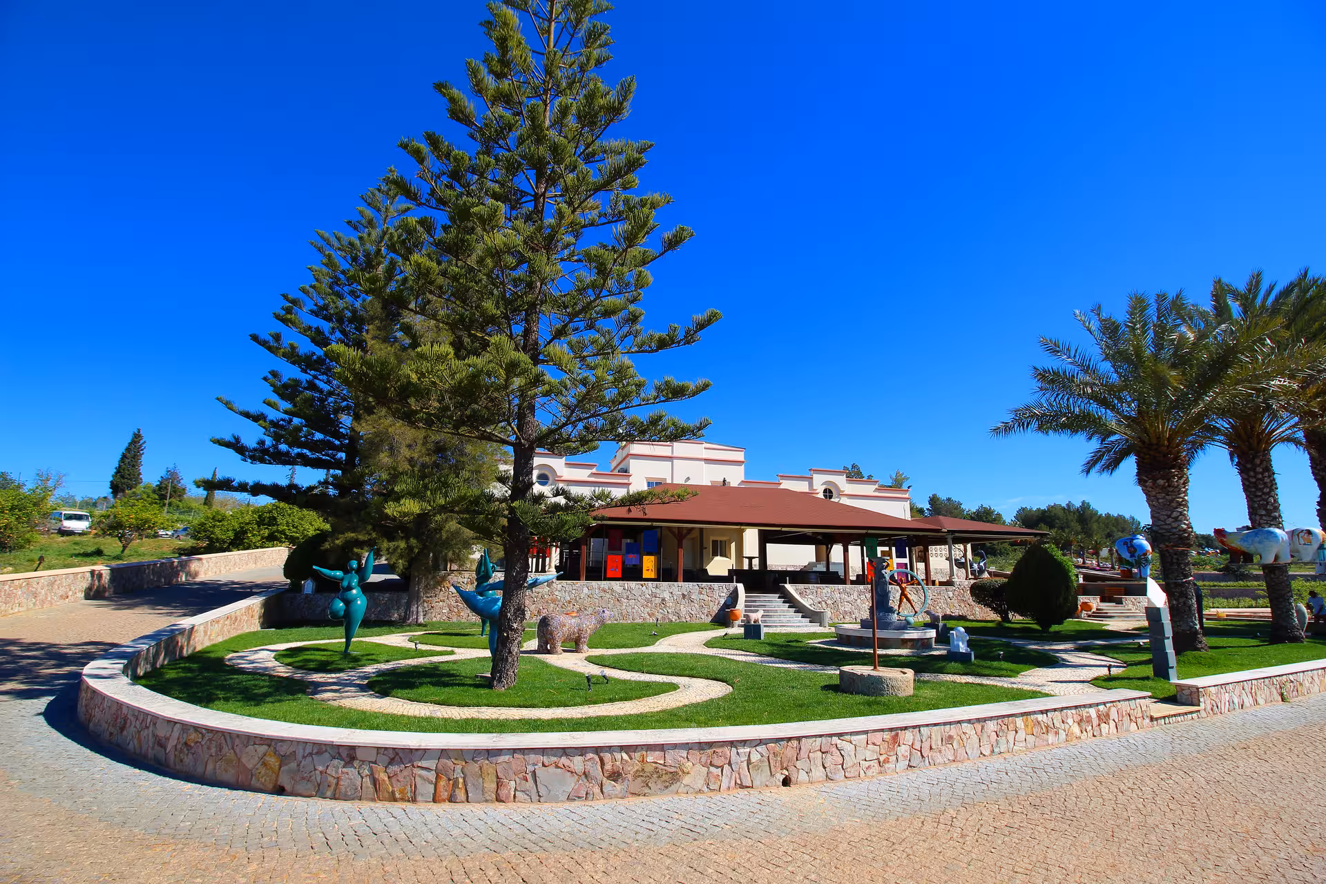Scenic winery estate entrance with lush gardens and sculptures perfect for a guided free-flow wine tasting tour