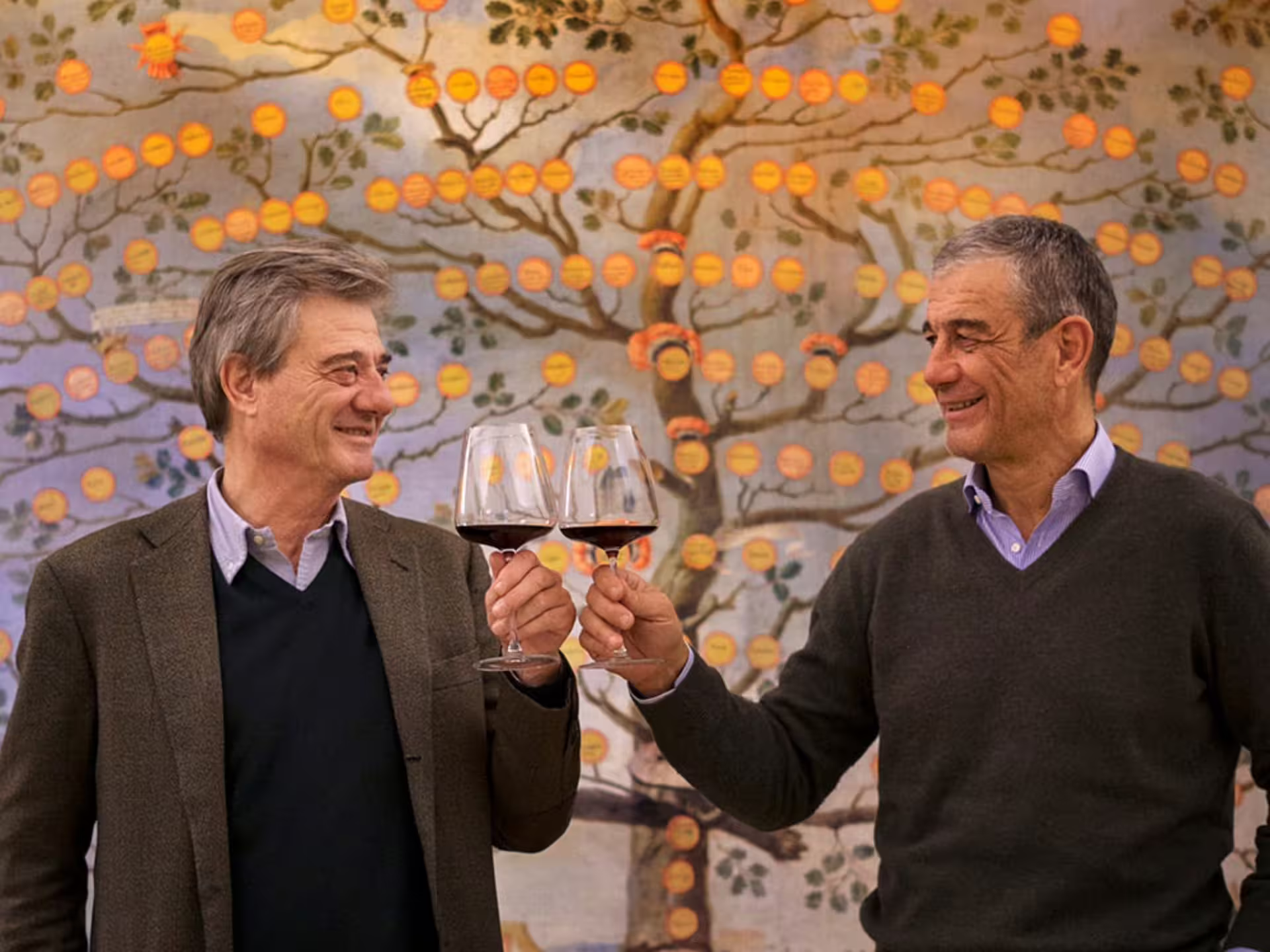 Two men toasting with wine glasses at a winery near Grosseto, showcasing a vibrant background mural.