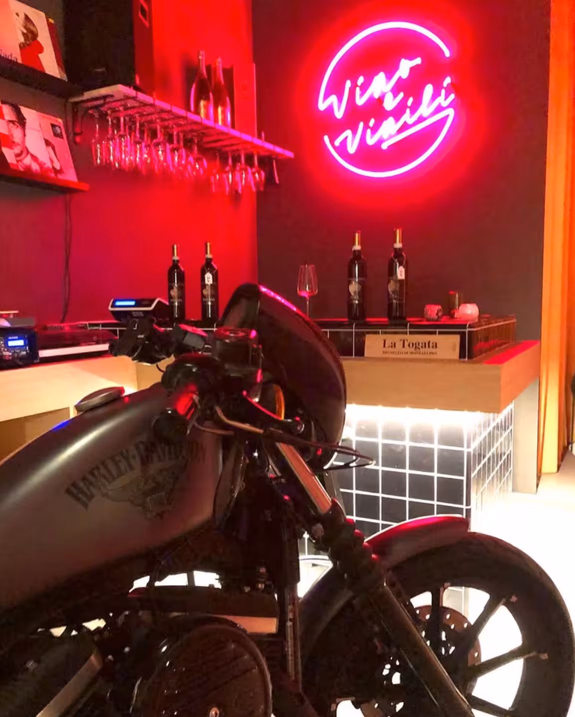 Neon wine bar in Rome with motorcycle décor, setting for Wines & Vinyl vintage experience and tastings