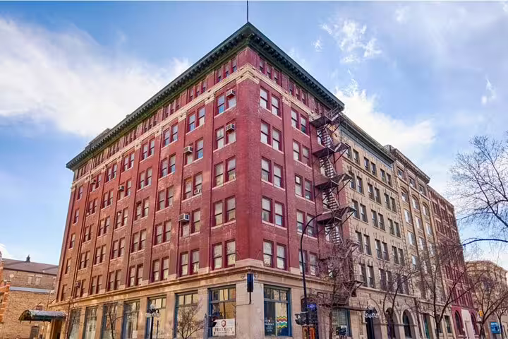 Historic red brick multi-story building in downtown Winnipeg with fire escape stairs on corner facade