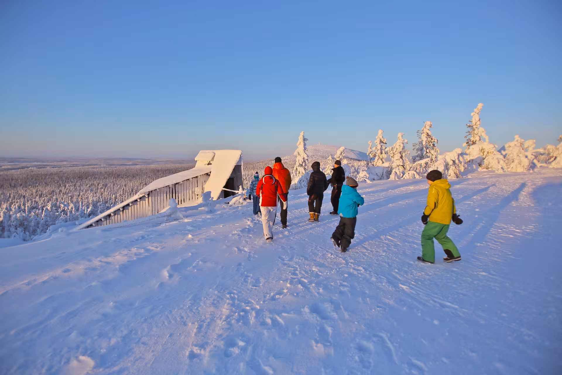 Group of tourists walking towards a snow-covered cabin in Lapland, enjoying a winter gemstone mining tour.
