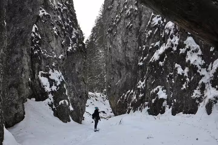 Hiker walking through a narrow snow-covered rocky gorge in Piatra Craiului National Park in winter