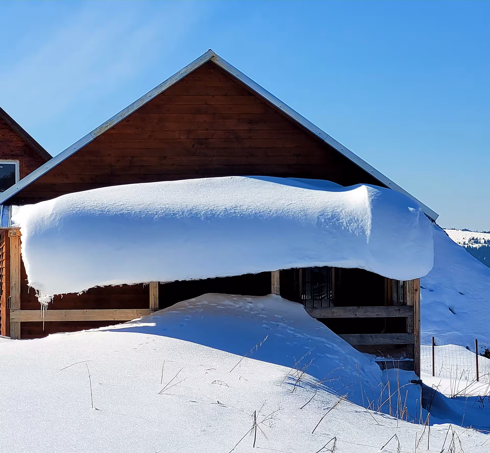 Heavy snow accumulation on wooden barn roof during winter in Cluj-Napoca mountain region
