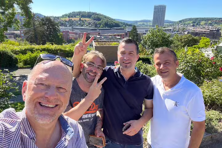 Smiling friends at a Winterthur panorama spot on a self-guided scavenger hunt tour, with city skyline behind