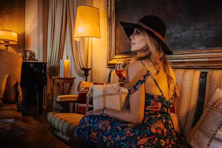 Woman enjoying an aperitif in a Venetian palace with elegant decor and soft lighting, highlighting luxury and relaxation.