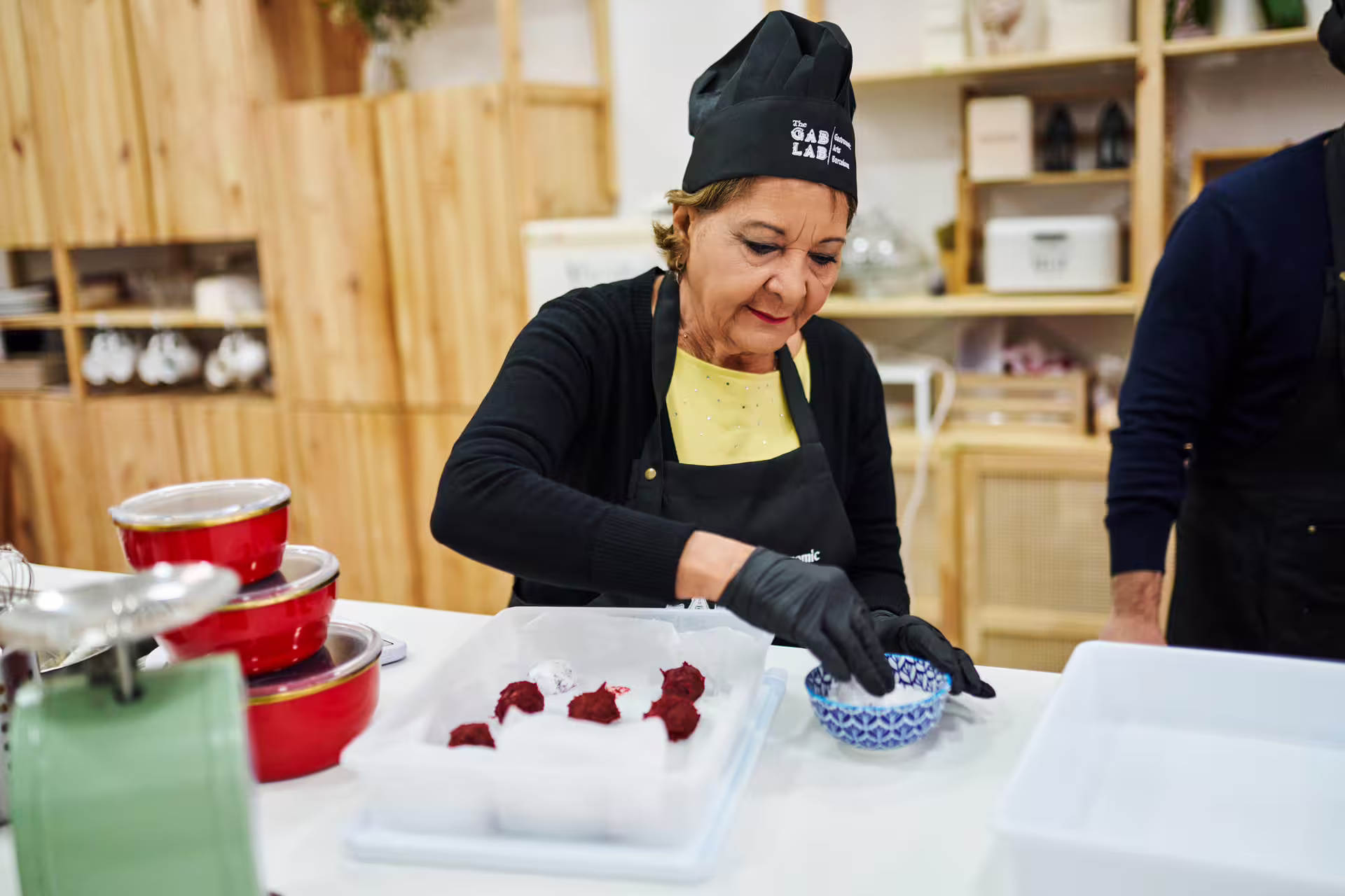 A woman in a chef's hat skillfully prepares desserts at the Sweet Escape: Bake & Take Workshop, surrounded by baking tools.