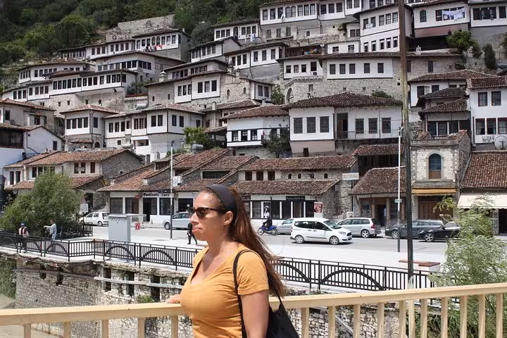 Woman enjoys the scenic view of Berat's traditional hillside houses on a sunny day trip in Albania.