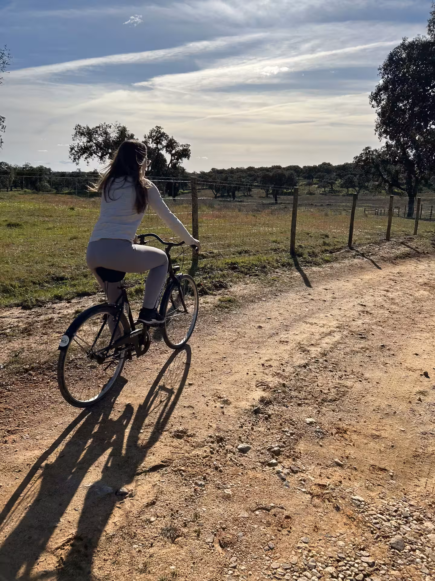 Woman biking along a rustic path surrounded by the tranquil beauty of Alentejo Montado's natural scenery.