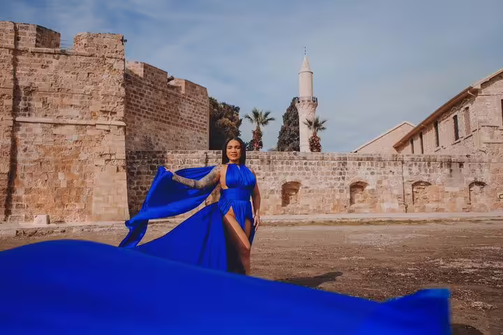 Woman in a blue gown stands before historic Ayia Napa architecture, captured in a private photoshoot.