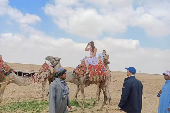 Woman riding a camel across the Giza Plateau desert on a private Giza Pyramids and Sphinx camel ride tour