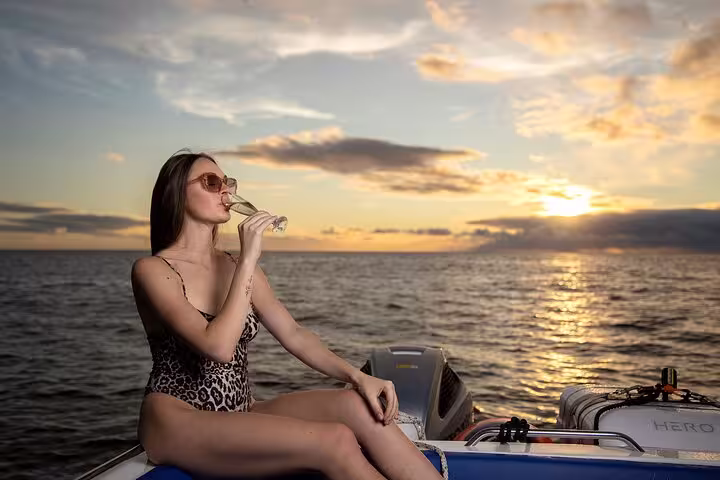 Woman relaxes with champagne on a private cruise, enjoying a stunning sunset on an adventure escape.