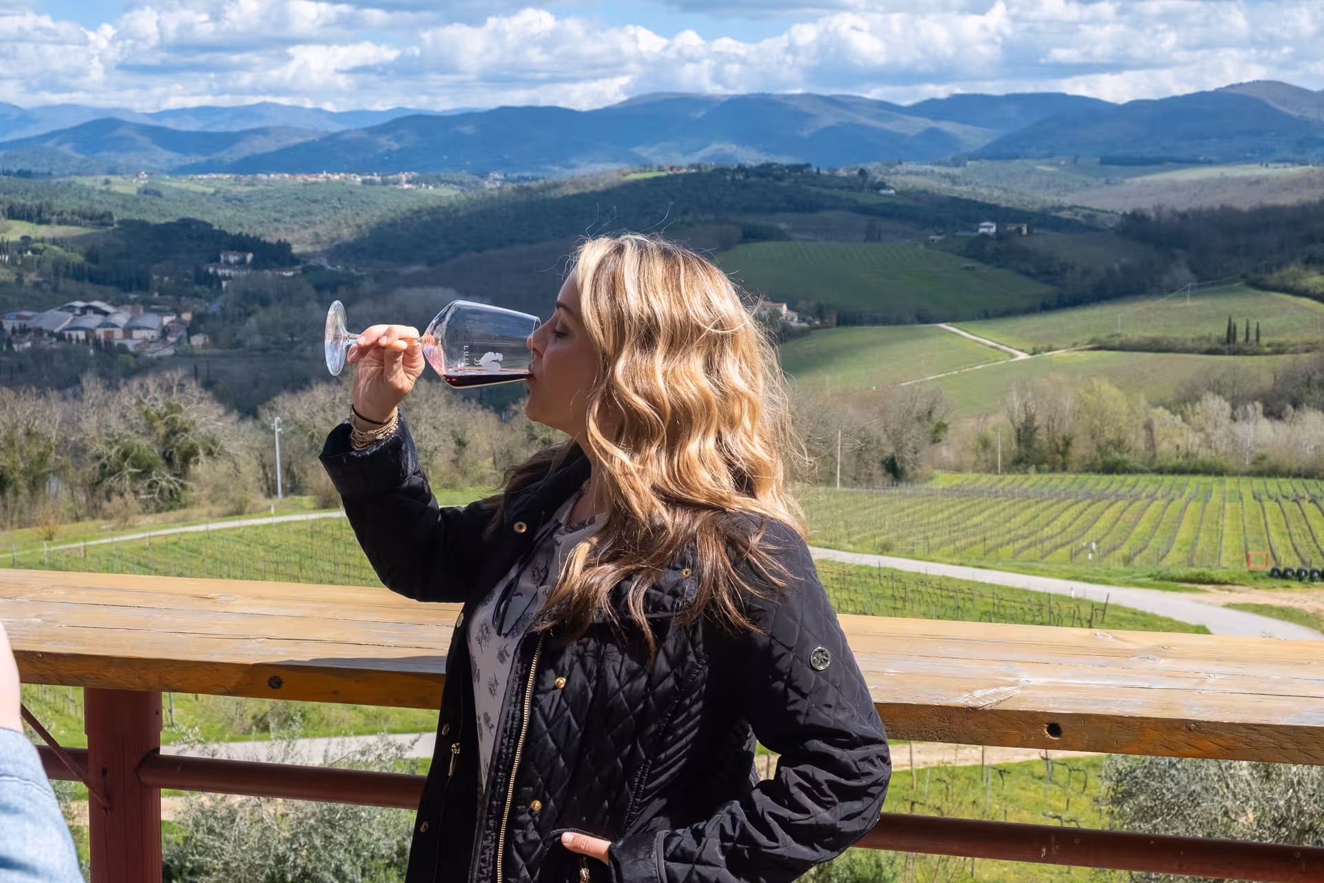 Woman savoring Chianti Classico wine with panoramic vineyard views on a private vintage FIAT 500 tour.