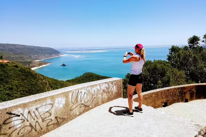 Woman taking photo of stunning coastal view at Arrábida Natural Park, perfect for a snorkeling adventure near Lisbon.