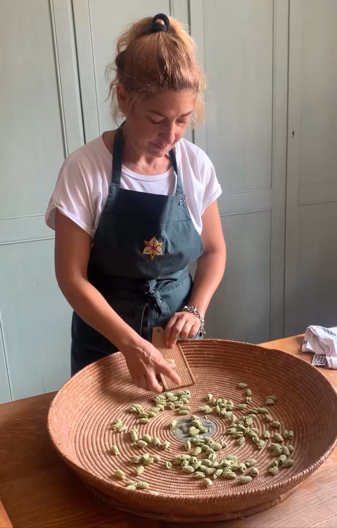 Woman crafting traditional pasta in Oristano workshop, showcasing hands-on culinary skills in a rustic kitchen setting.