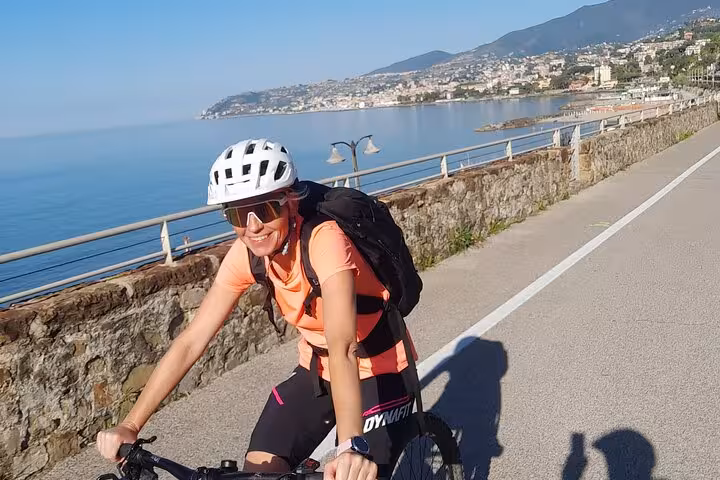 Woman cycling along the picturesque coastal path in Sanremo with stunning sea views on the Riviera dei Fiori tour.