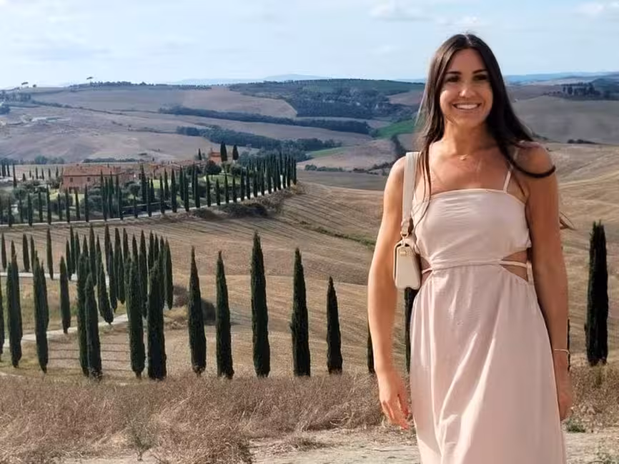 Woman standing amidst the stunning cypress-lined landscapes of Tuscany near Montepulciano.