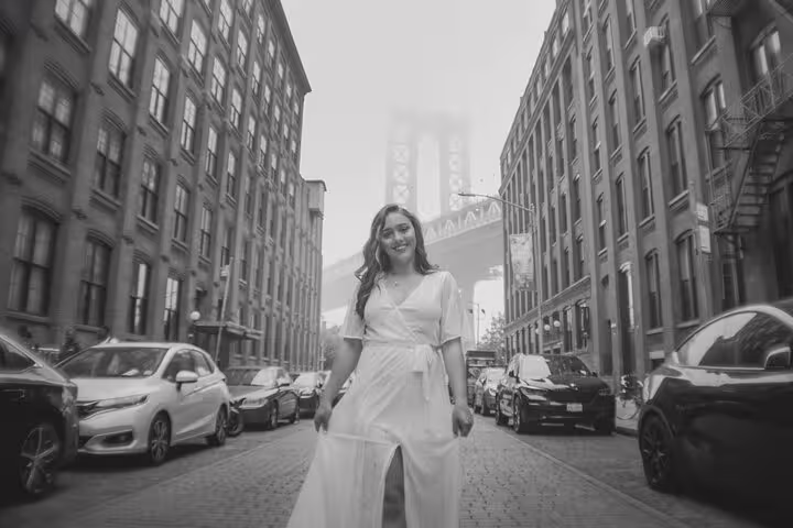Woman posing on DUMBO cobblestone street with Manhattan Bridge backdrop, private Brooklyn photo tour in NYC