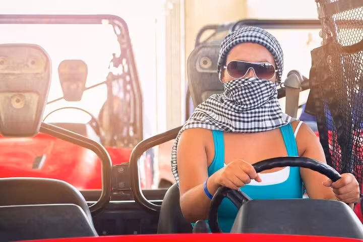 Woman driving dune buggy in Hurghada with scarf and sunglasses, Red Sea desert safari along mountains
