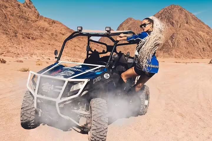Woman riding dune buggy in Sinai mountains, Sharm El Sheikh family desert safari tour with sand spray