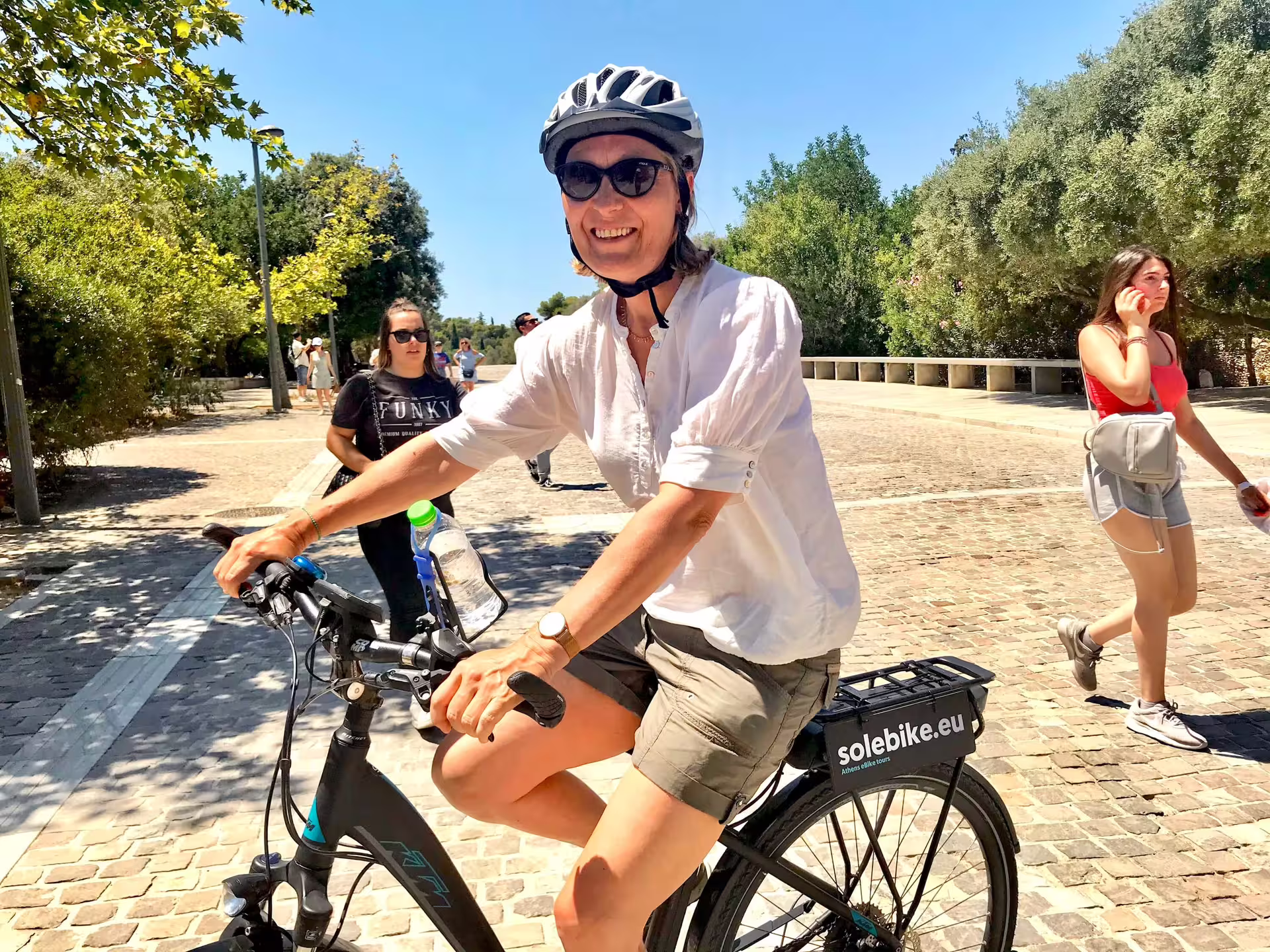 Woman riding an e-bike through Athens on a sunny day, enjoying the historical sights and local flavors.