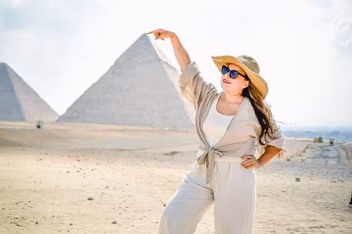 Woman posing in the desert with Giza Pyramids on a Cairo and pyramids full-day tour from Sharm El Sheikh by bus