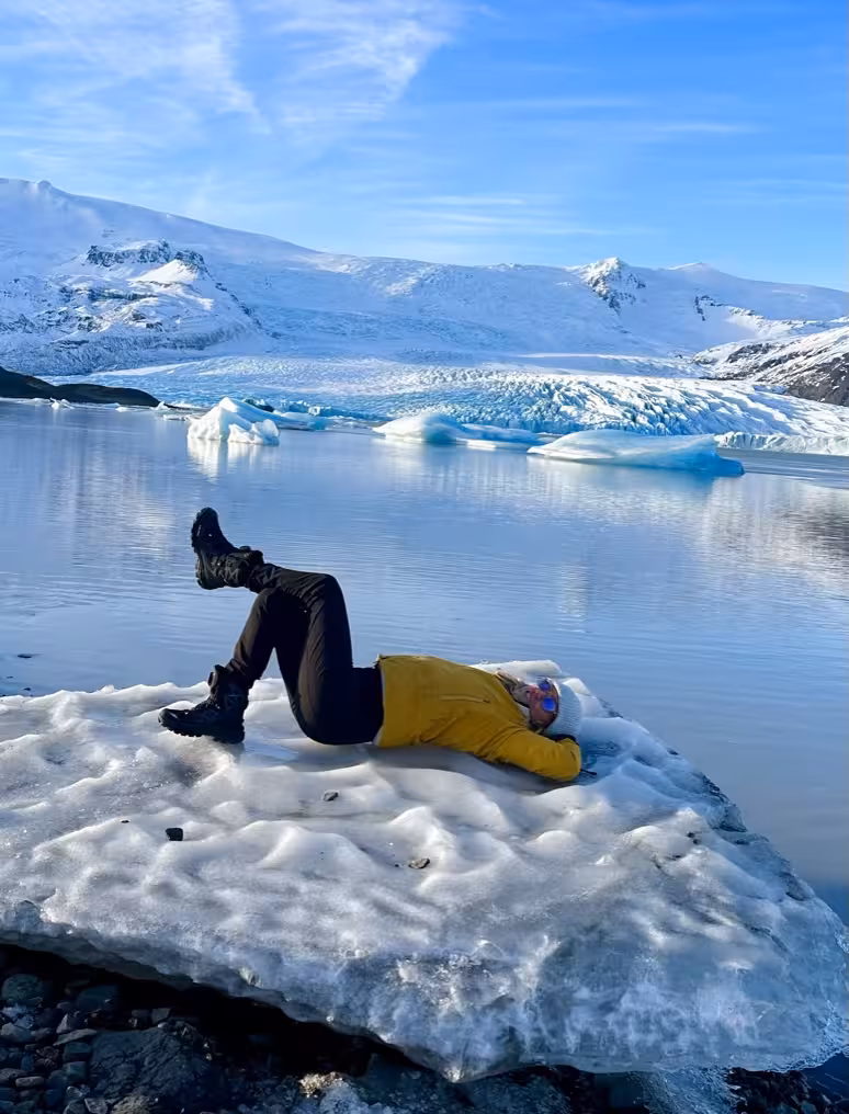 Woman relaxing on an ice floe at a serene glacier lagoon, highlighting the adventure of the Iceland women-only tour.
