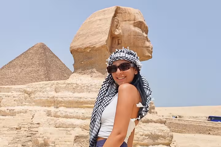 Woman posing in front of the Great Sphinx with pyramids in the background.