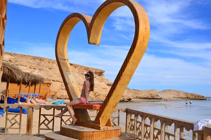 Woman sitting in heart-shaped photo spot at Orange Bay, Hurghada, on snorkeling cruise with lunch and drinks
