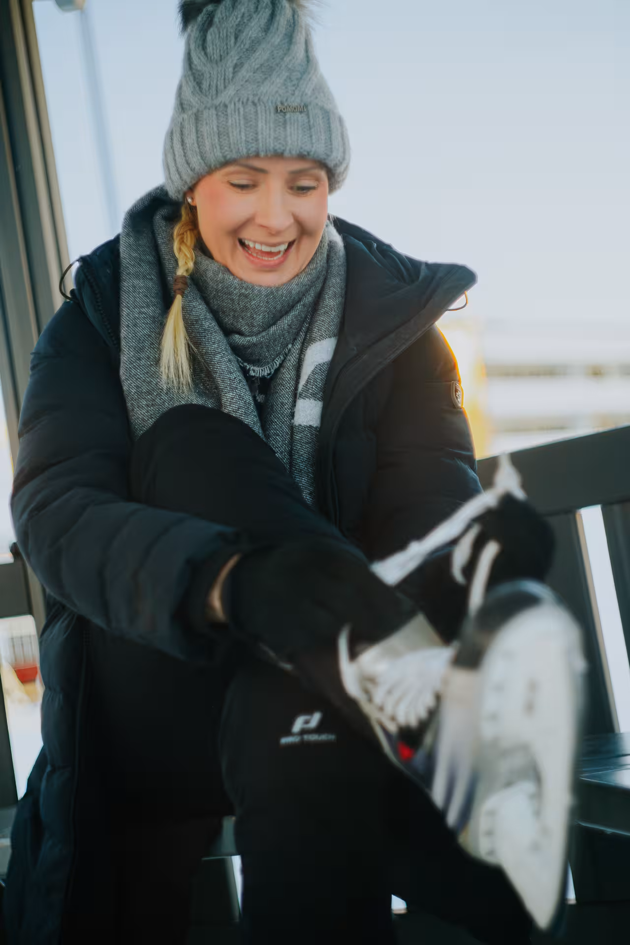 Woman smiling as she puts on ice skates in Rovaniemi, preparing for a memorable private photography session.