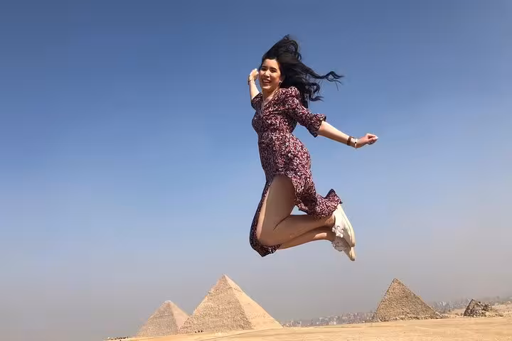 Woman jumping with Giza Pyramids in background on private tour, perfect for ATV desert ride, camel trek and Nile cruise