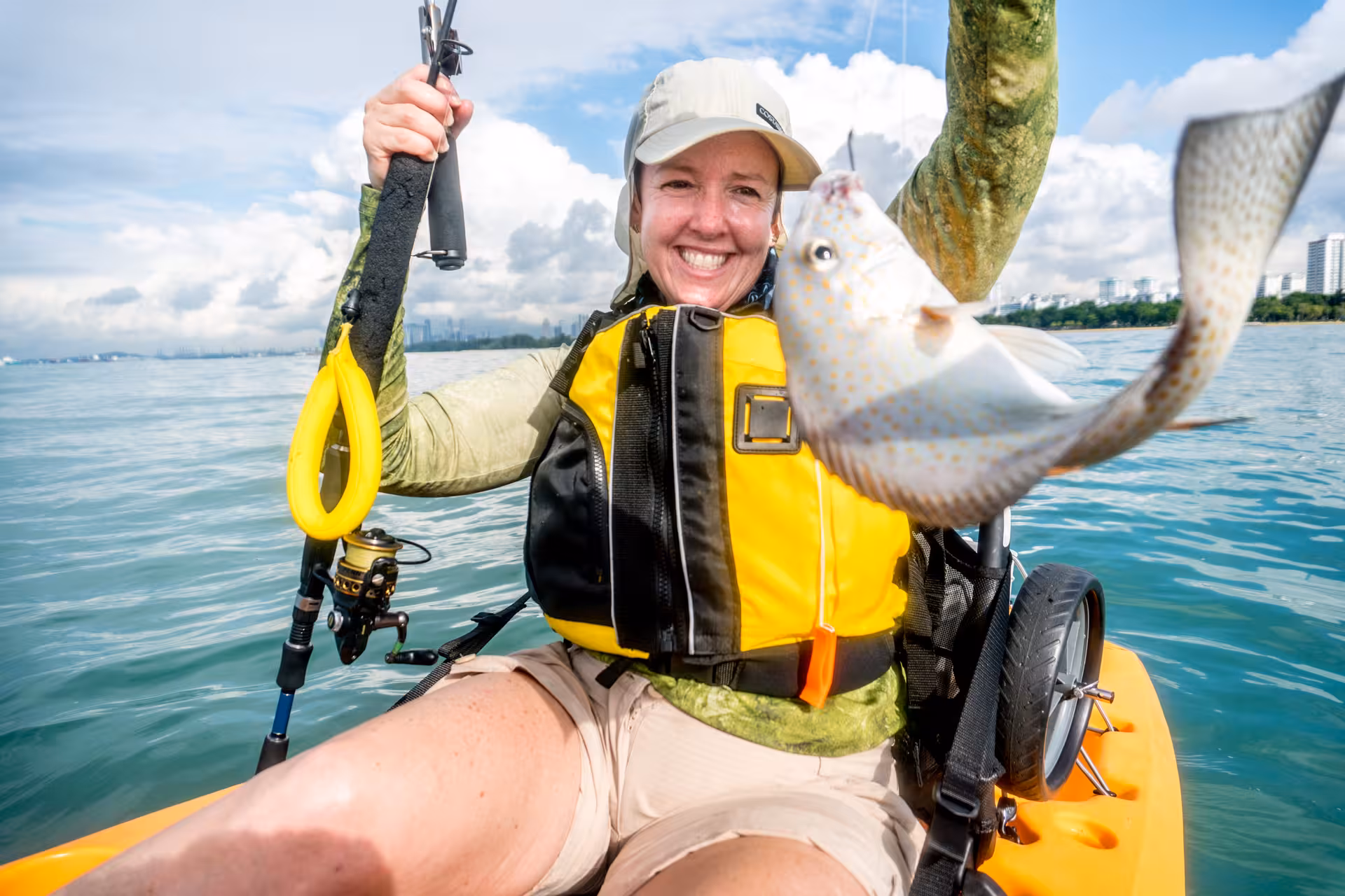 Smiling woman proudly displays her catch on a kayak fishing tour at the scenic East Coast waters.