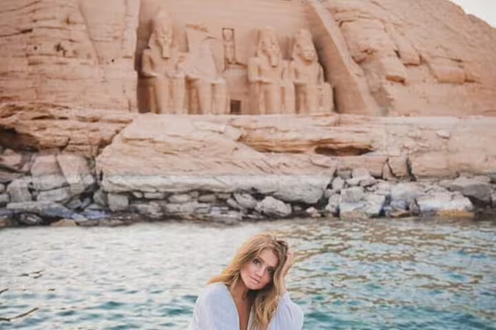 Woman by Lake Nasser with Abu Simbel temple in background, scenic highlight of a day trip from Aswan