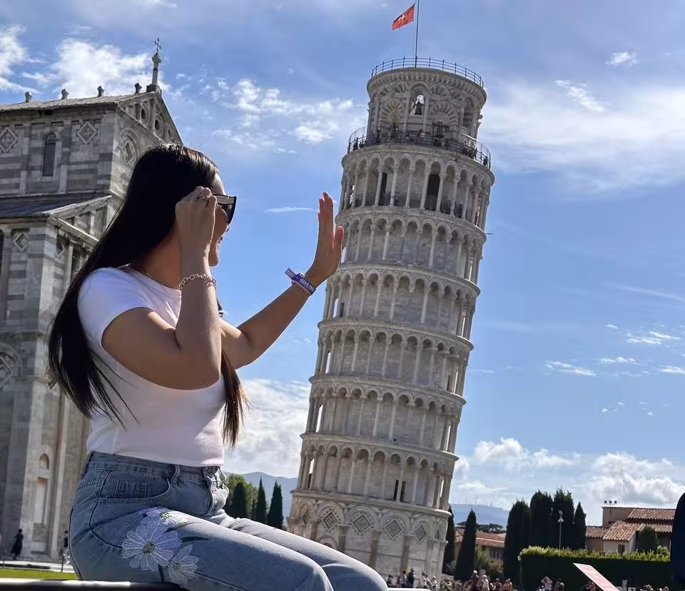 Woman playfully interacting with the Leaning Tower of Pisa, capturing a fun moment on a Pisa day tour.