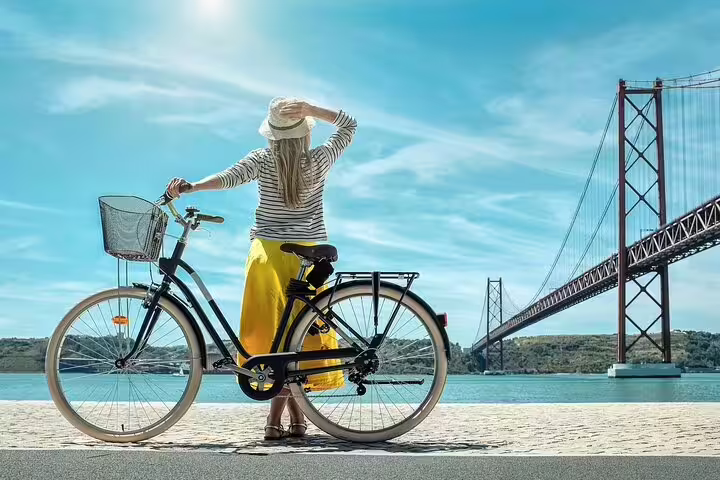 Woman enjoys scenic view of Lisbon's iconic bridge during a private bike tour, highlighting Belem's stunning waterfront.