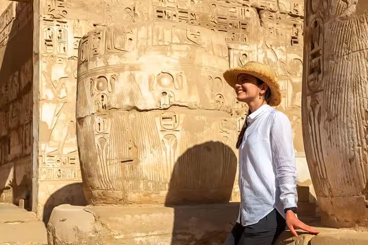 Woman in sunhat admiring ancient hieroglyphs at Luxor Temple, part of Hurghada day trip with lunch included