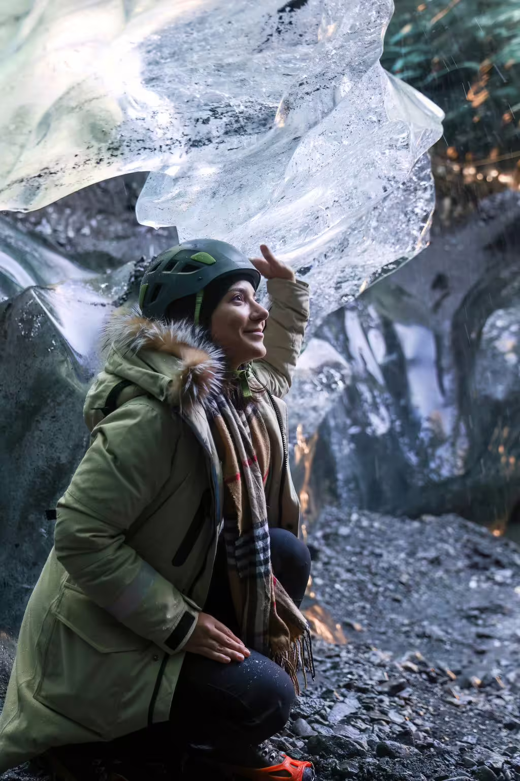 A woman in a helmet marvels at crystal clear ice formations inside an Iceland sapphire ice cave on an early bird guided tour.