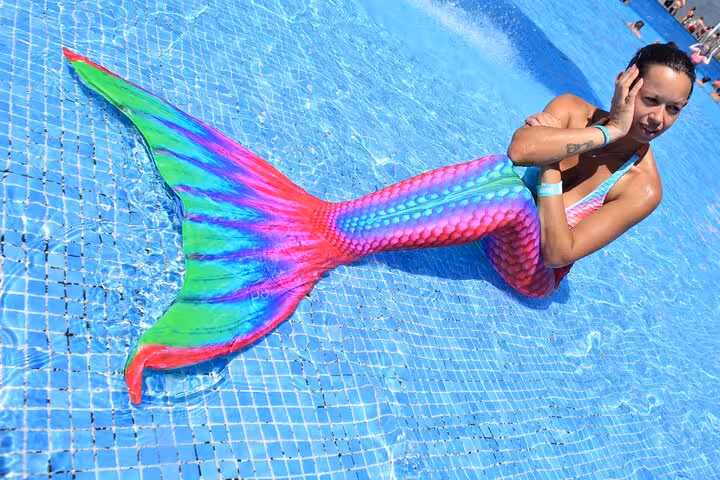 Woman poses with colorful mermaid tail in Hersonissos pool, capturing the essence of a private mermaid photoshoot.