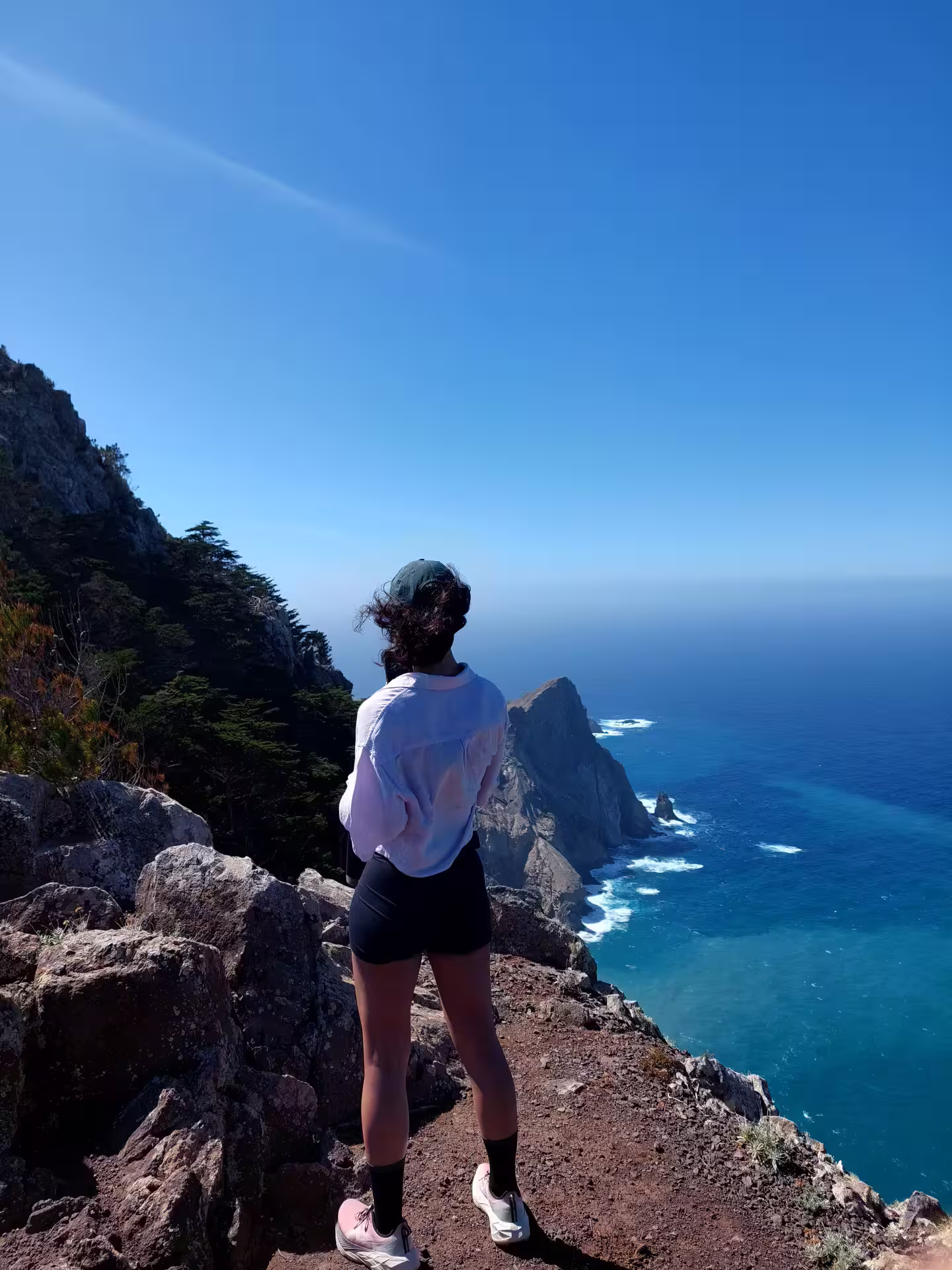 Woman enjoying breathtaking ocean view from rocky cliff on a customized hiking tour adventure, perfect for nature enthusiasts.