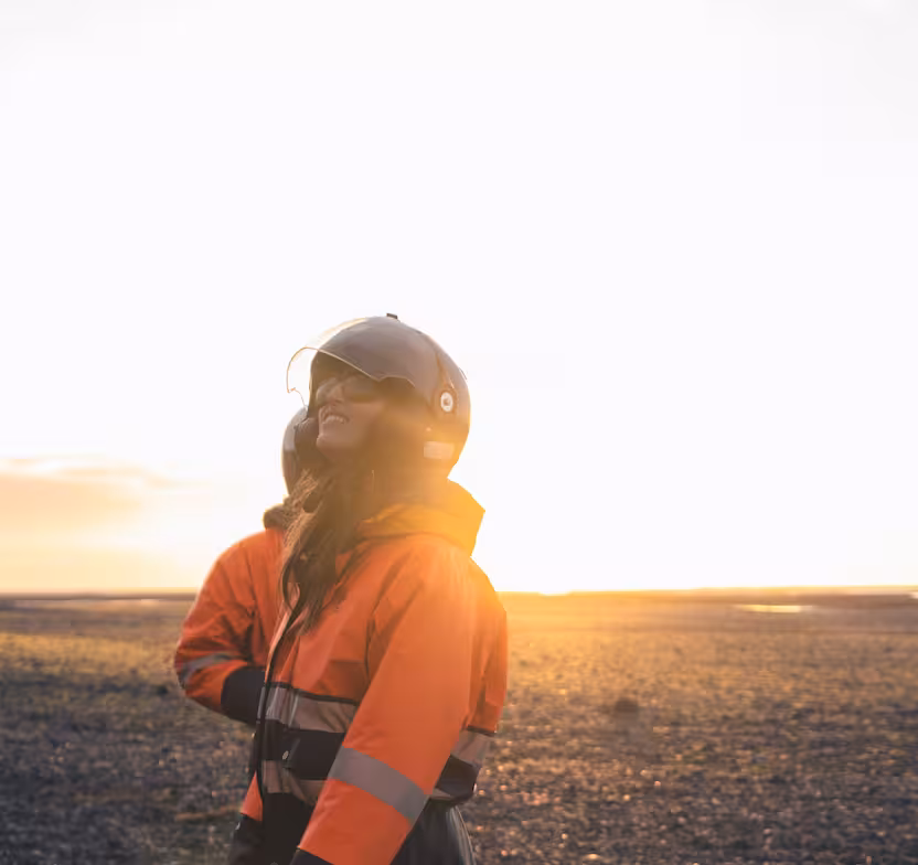 Woman in orange high-visibility jacket and helmet smiling during Iceland buggy tour at sunset