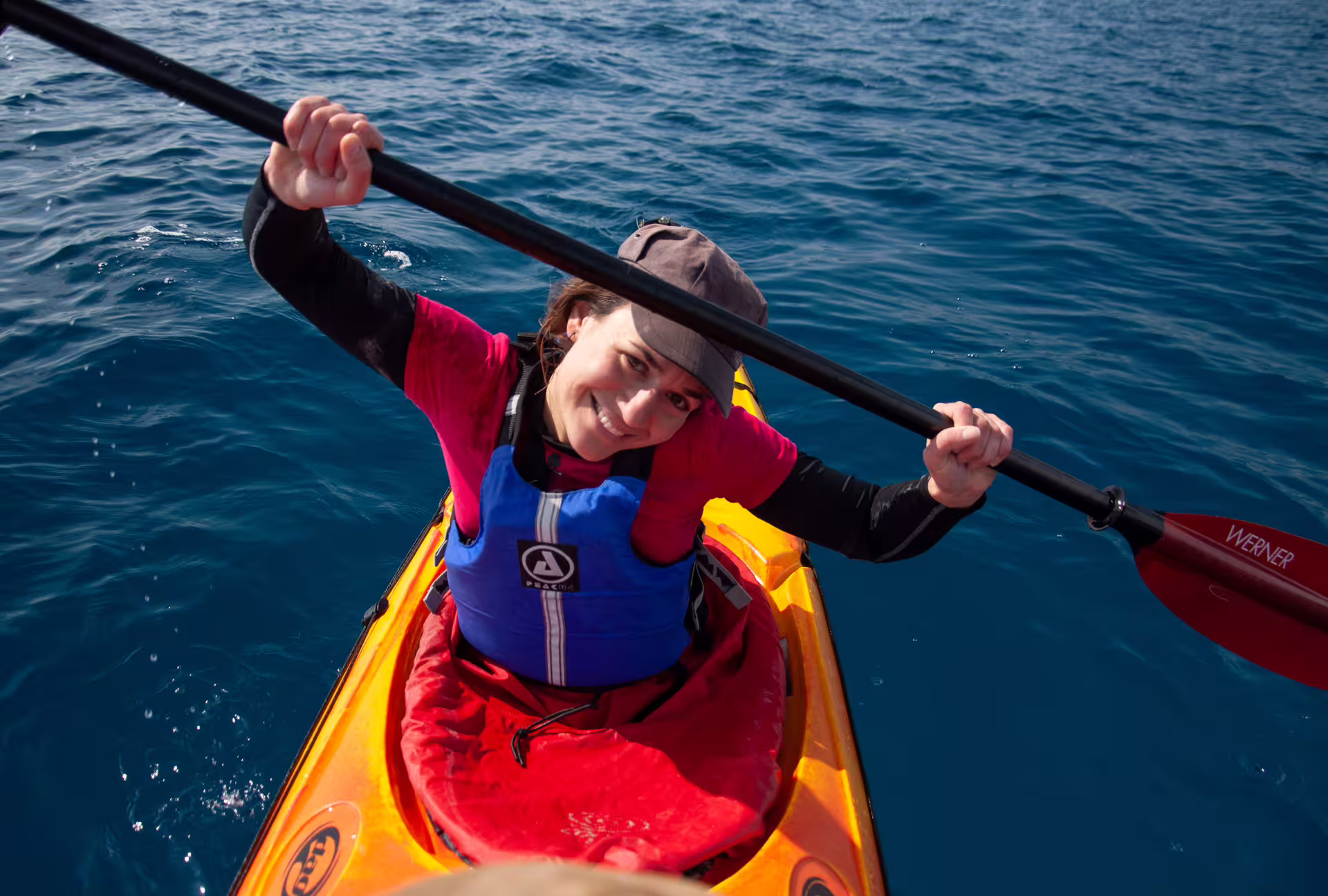 Smiling woman paddling a sea kayak on clear blue water near Kardamyli and Stoupa, Mani Peninsula Greece