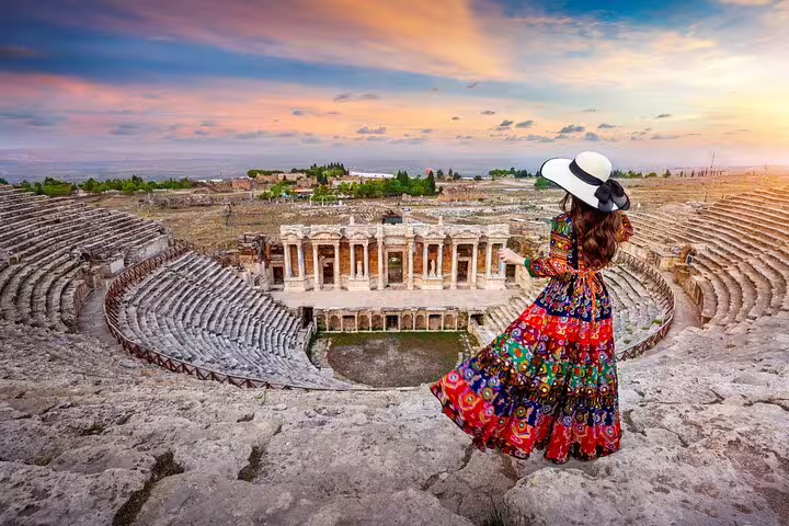 Woman in colorful dress overlooking the ancient Roman theater in Pamukkale at sunset during a cultural tour.