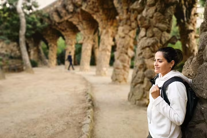 Woman enjoys a serene moment in Park Güell, Barcelona, surrounded by iconic stone arches during a private city tour.