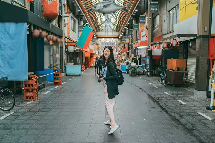 Woman posing in vibrant Osaka market street during a private photoshoot with a professional photographer.