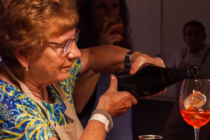 Woman pouring a sparkling drink during an Italian aperitivo experience in Barcelona, showcasing cocktail-making skills.