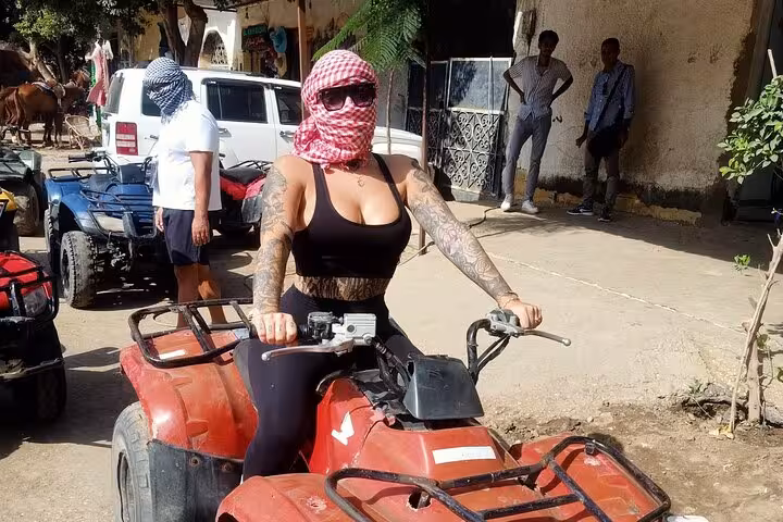 Woman on a red ATV in Cairo wearing a keffiyeh, starting quad bike adventure for lunch and shopping tour